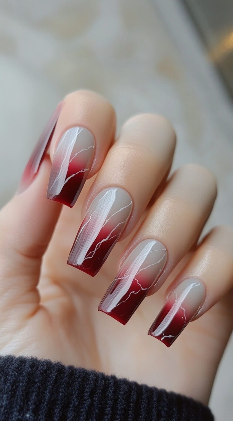 Long coffin-shaped nails with a red ombre base and delicate white vein-like lines flowing downward.