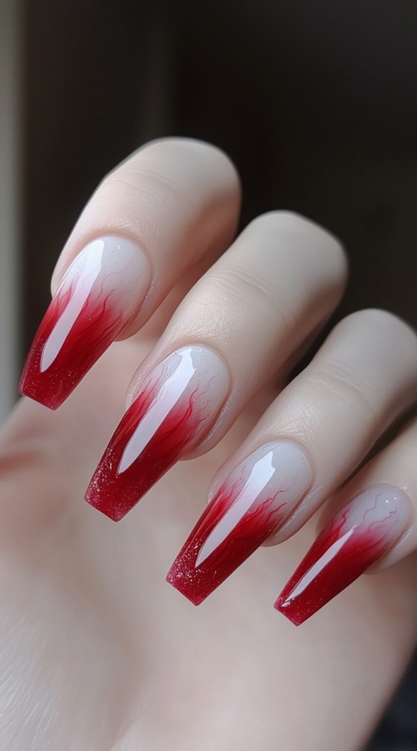 A hand with long red ombre coffin nails, where the red tips appear like soft flames trailing upward.