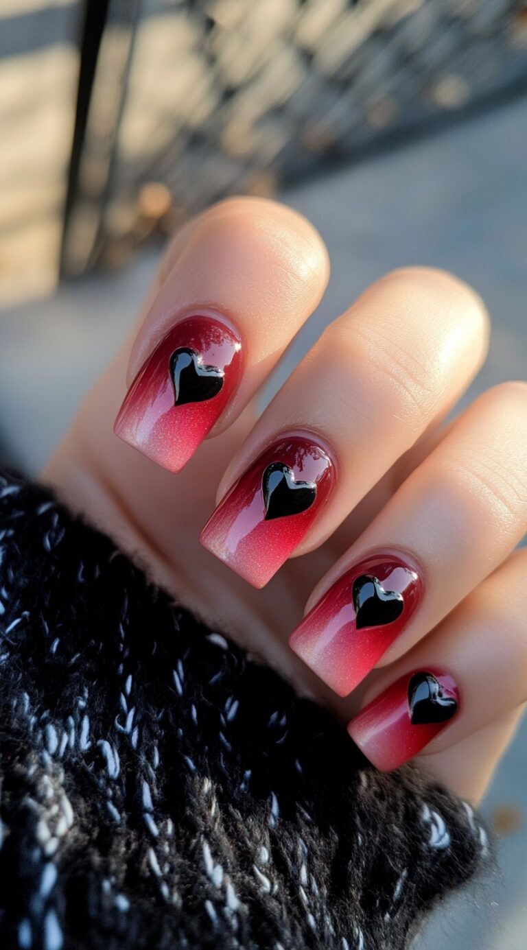 Square-shaped red ombre nails with glossy black heart accents on each fingertip.