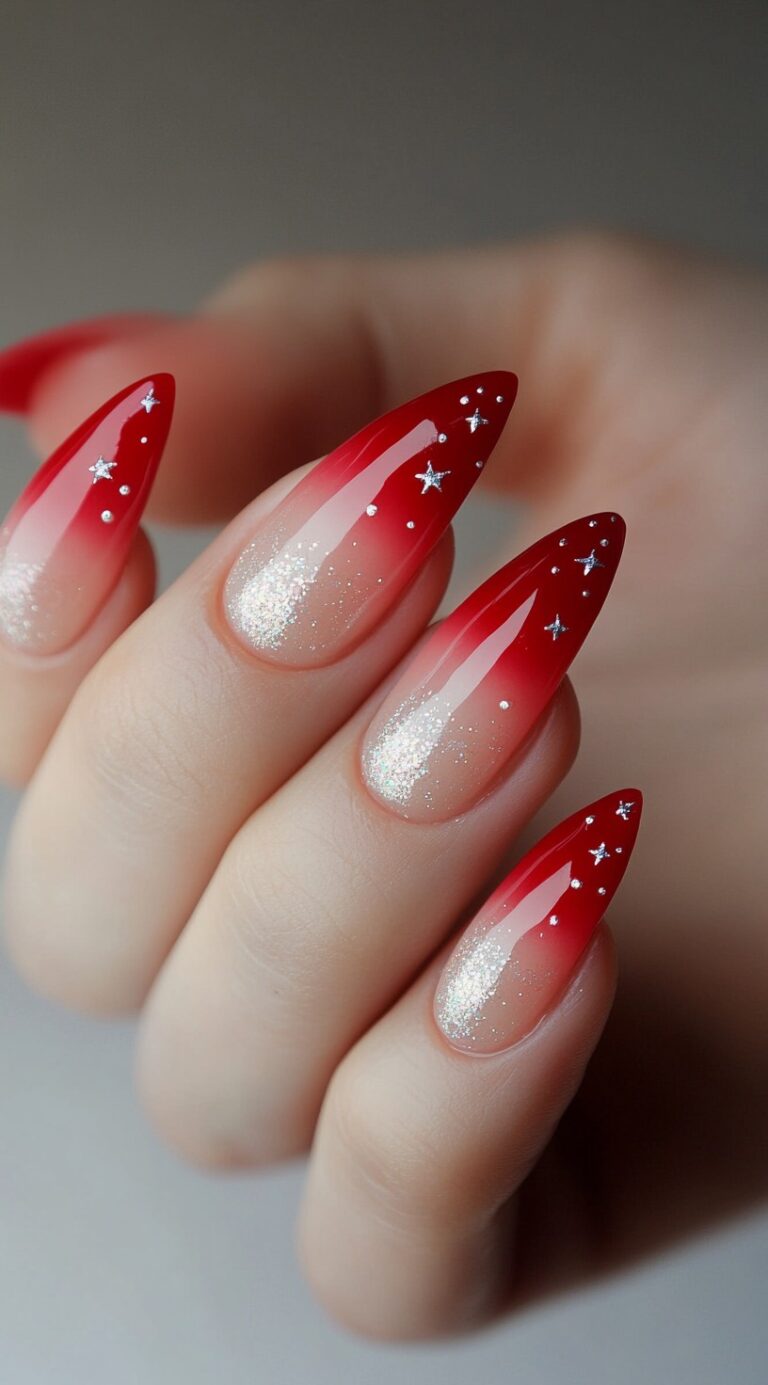 Almond-shaped red ombre nails with scattered silver glitter and tiny star embellishments.