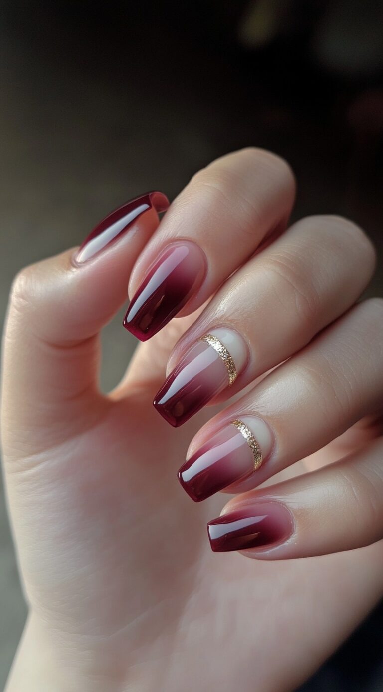 Tapered square nails with a red ombre finish are accented by thin gold glitter bands near the cuticles.